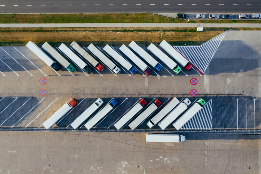 Aerial view of semi-trucks and trailers parked in angled rows in a distribution center yard