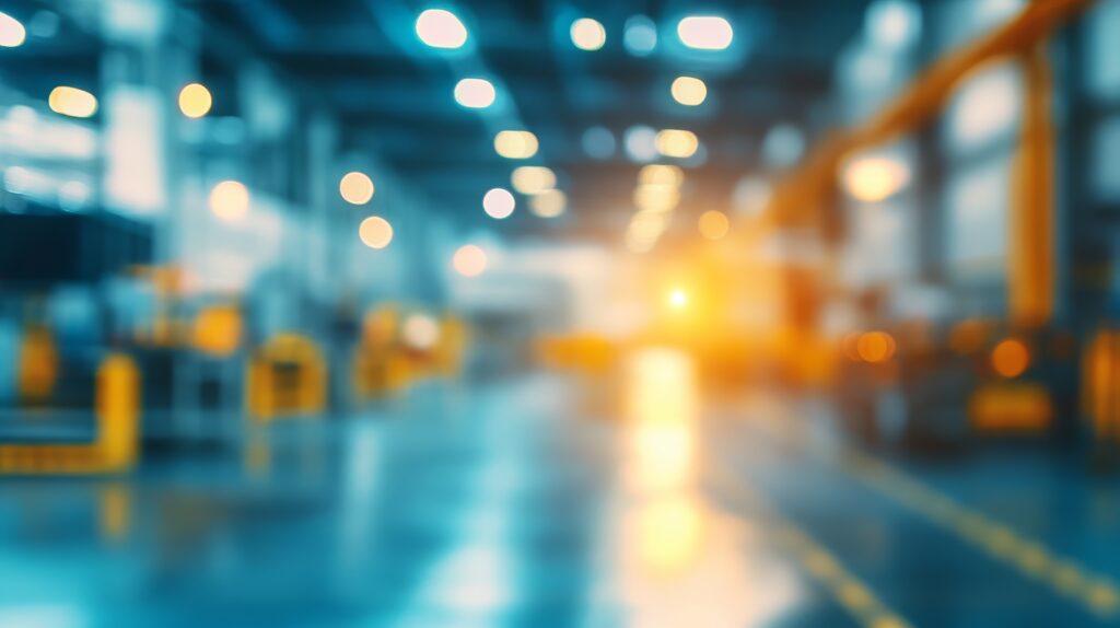 Blurred industrial factory interior with blue ambient lighting, a bright orange glow, and reflections on the floor.